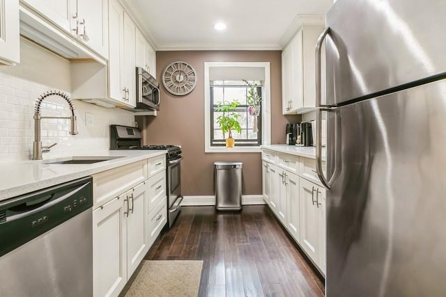 kitchen featuring dark wood-style flooring, decorative backsplash, appliances with stainless steel finishes, white cabinetry, and a sink