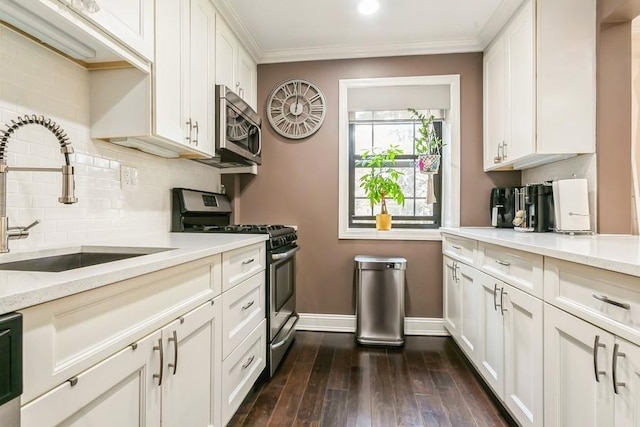 kitchen featuring light stone counters, crown molding, stainless steel appliances, white cabinets, and a sink