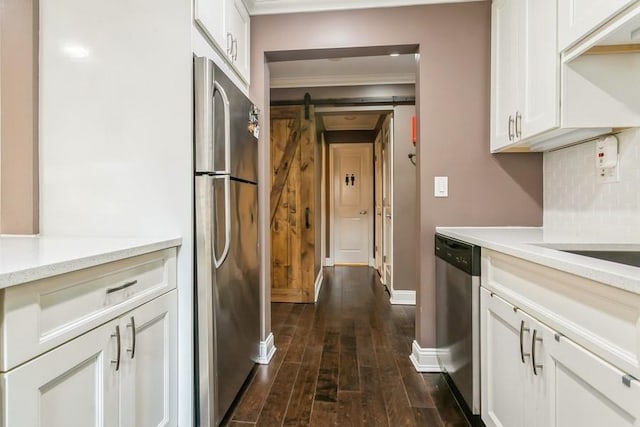 kitchen featuring dark wood-style flooring, light countertops, a barn door, appliances with stainless steel finishes, and white cabinets