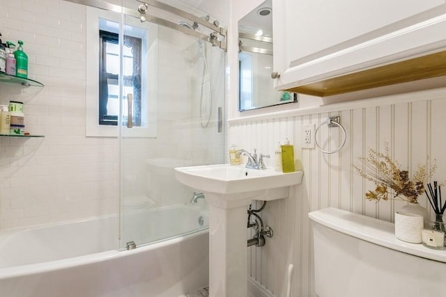 full bathroom with toilet and bath / shower combo with glass door