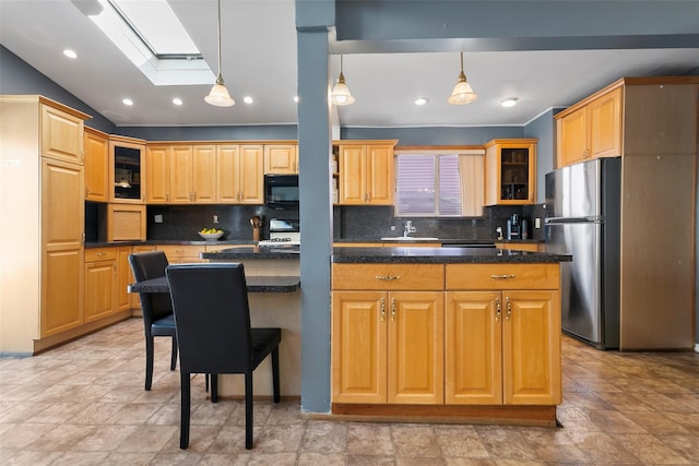 kitchen featuring dark countertops, glass insert cabinets, a sink, and freestanding refrigerator