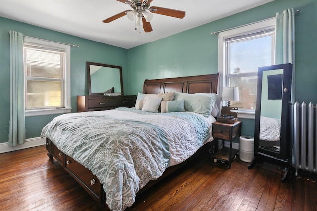 bedroom featuring baseboards, multiple windows, dark wood finished floors, and radiator heating unit