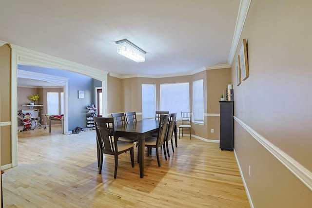 dining area with light wood finished floors, baseboards, and ornamental molding