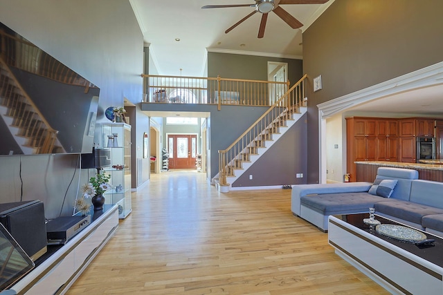 living area with light wood-style flooring, ornamental molding, stairway, and baseboards