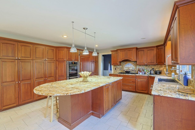 kitchen featuring brown cabinetry, decorative backsplash, a center island, light stone countertops, and stainless steel appliances