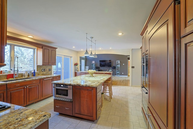 kitchen with decorative backsplash, a kitchen island, open floor plan, oven, and a sink