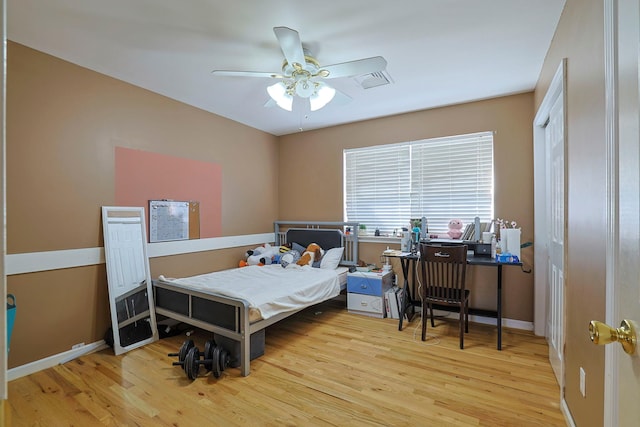 bedroom featuring a ceiling fan, visible vents, baseboards, and wood finished floors