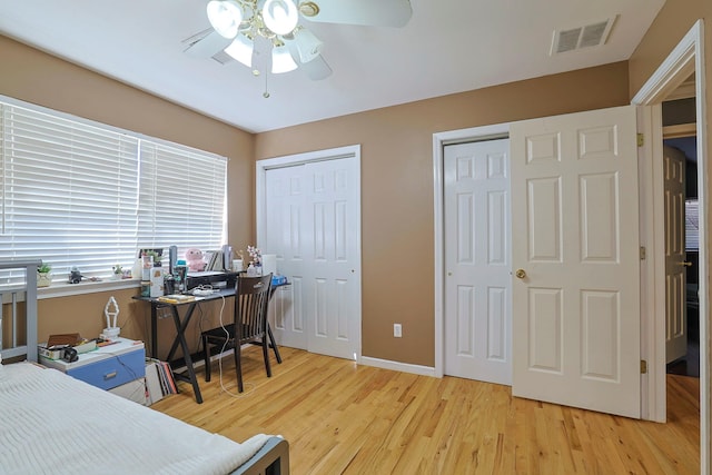 office space featuring baseboards, wood finished floors, visible vents, and a ceiling fan