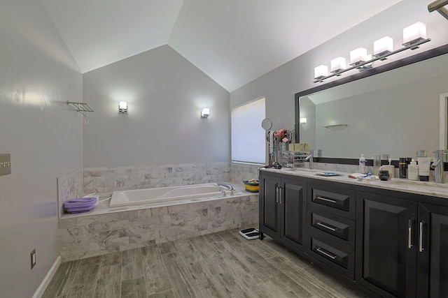 full bath featuring double vanity, a garden tub, vaulted ceiling, and wood finished floors