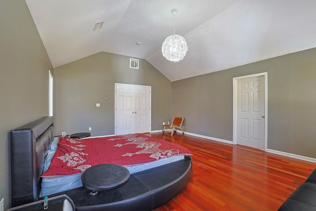 bedroom featuring lofted ceiling, wood finished floors, visible vents, and a chandelier