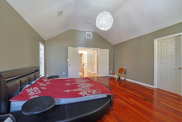 bedroom with vaulted ceiling, wood finished floors, visible vents, and a chandelier