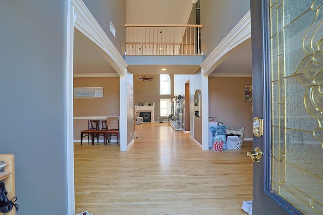 entryway with ornamental molding, wood finished floors, and a glass covered fireplace