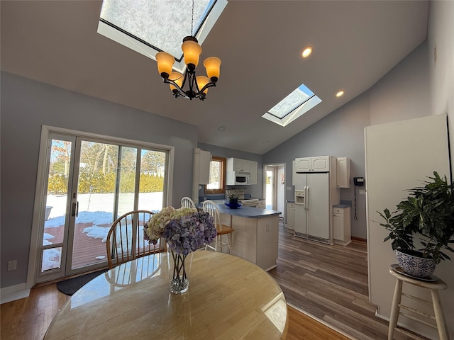 dining space featuring a skylight, dark wood finished floors, recessed lighting, an inviting chandelier, and high vaulted ceiling