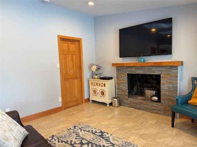 living room with recessed lighting, a stone fireplace, and baseboards