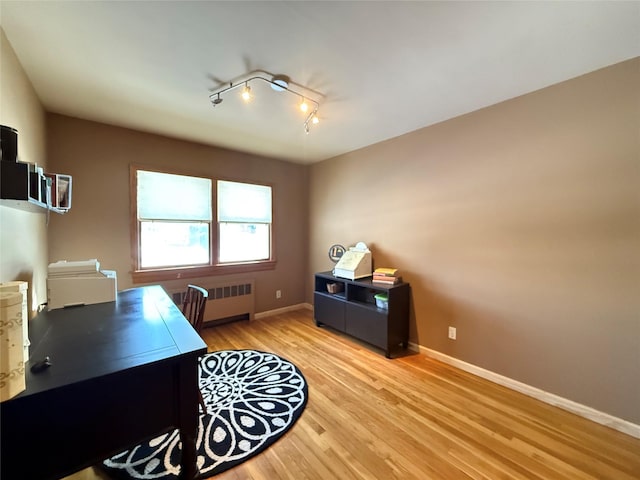 office area with light wood-type flooring, rail lighting, radiator heating unit, and baseboards