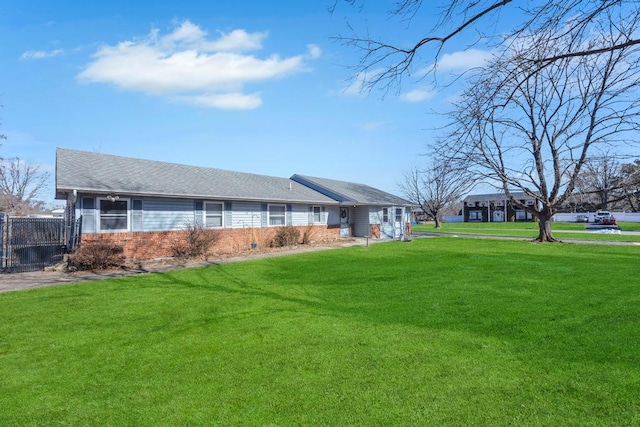 exterior space with brick siding, roof with shingles, fence, and a yard