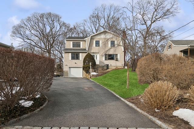 view of front of house with aphalt driveway, a front yard, an attached garage, and a gambrel roof