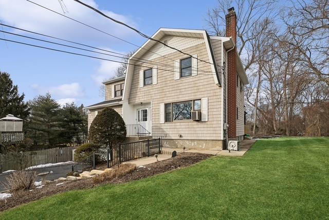 view of front of home featuring a front lawn, a chimney, cooling unit, and fence