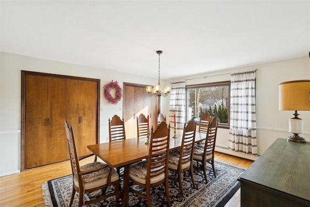 dining area featuring a chandelier, light wood-type flooring, and a baseboard heating unit