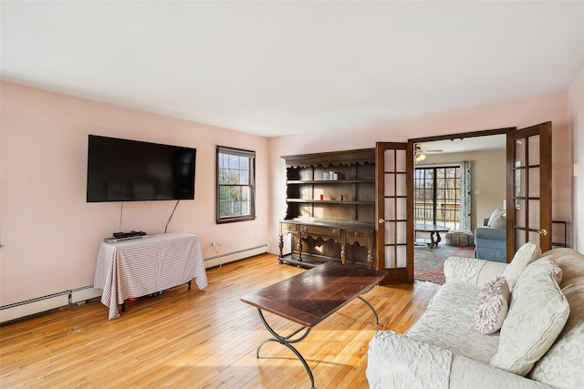 living room with light wood finished floors, a baseboard radiator, and a healthy amount of sunlight