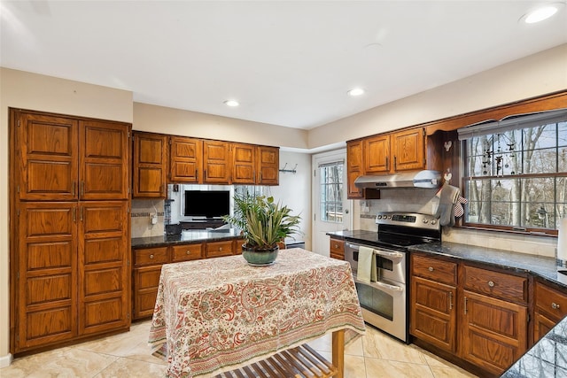 kitchen with under cabinet range hood, recessed lighting, double oven range, brown cabinets, and tasteful backsplash