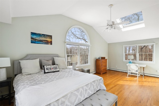 bedroom featuring a baseboard radiator, baseboard heating, lofted ceiling with skylight, light wood-style floors, and ceiling fan