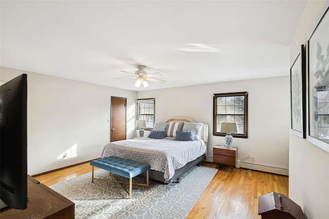 bedroom featuring light wood finished floors, baseboard heating, and baseboards