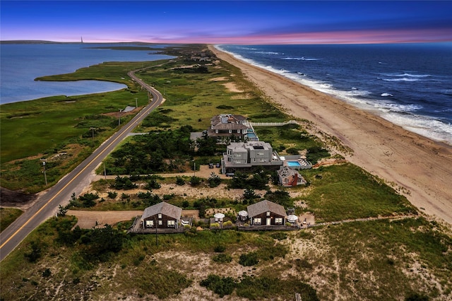 aerial view at dusk with a water view and a beach view