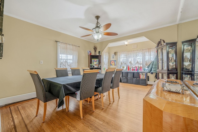 dining space featuring crown molding, a baseboard heating unit, a wealth of natural light, and light wood-style floors