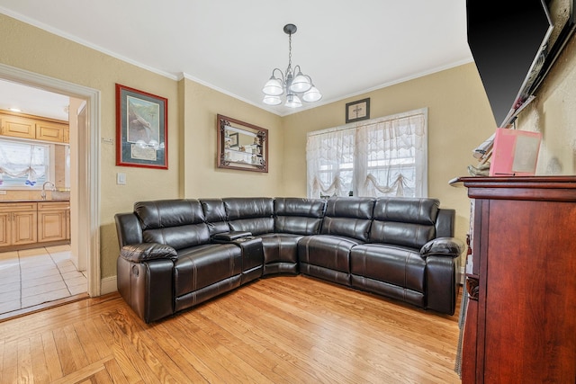 living area with light wood-style floors, ornamental molding, and a chandelier