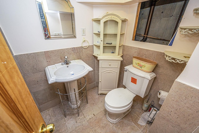 bathroom with toilet, tile walls, and wainscoting