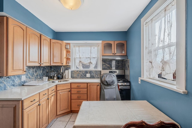 kitchen featuring gas range, plenty of natural light, under cabinet range hood, and glass insert cabinets