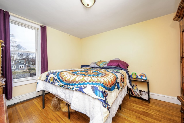 bedroom featuring a baseboard radiator, wood-type flooring, and baseboards