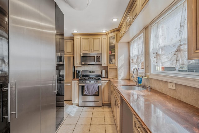 kitchen featuring tasteful backsplash, appliances with stainless steel finishes, glass insert cabinets, light tile patterned flooring, and a sink