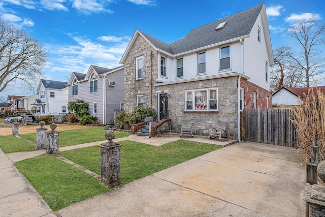 traditional-style home with stone siding, a residential view, fence, and a front yard