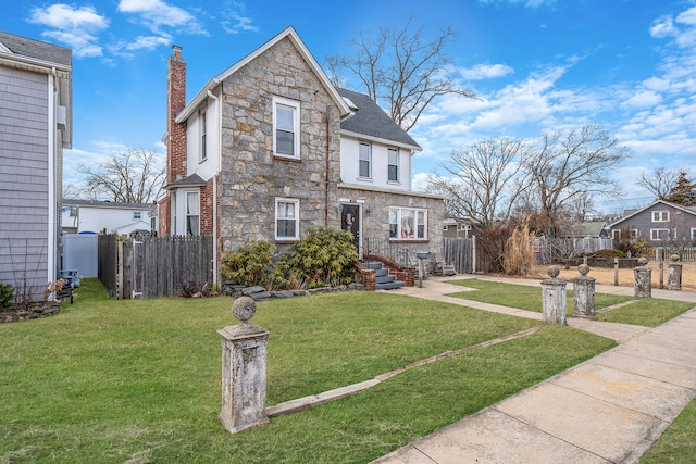 view of front facade with a front yard, stone siding, fence, and a chimney