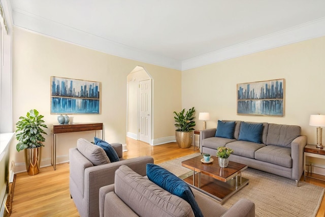 living area with arched walkways, light wood finished floors, baseboards, and crown molding