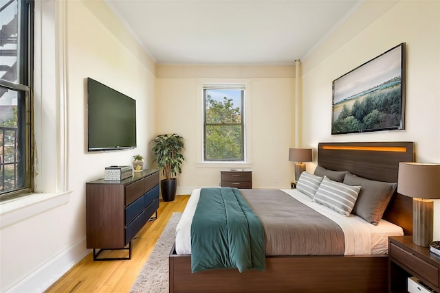 bedroom featuring light wood-type flooring, a baseboard radiator, and baseboards