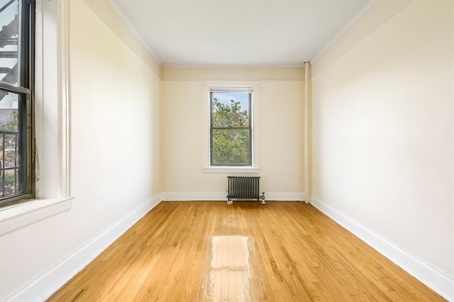 empty room with radiator, light wood-type flooring, and baseboards