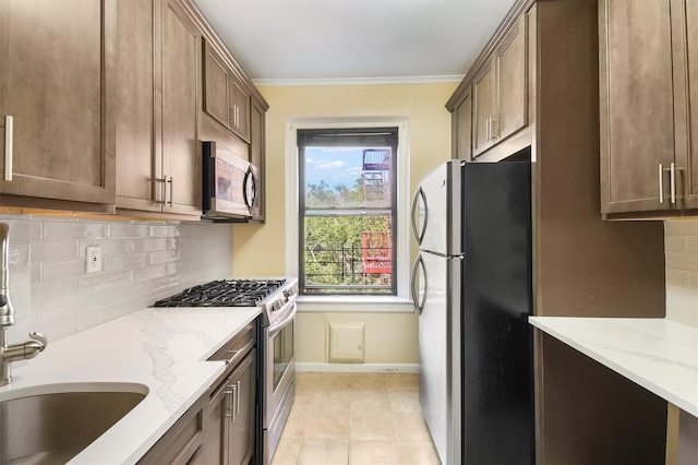 kitchen with tasteful backsplash, appliances with stainless steel finishes, light stone counters, and ornamental molding