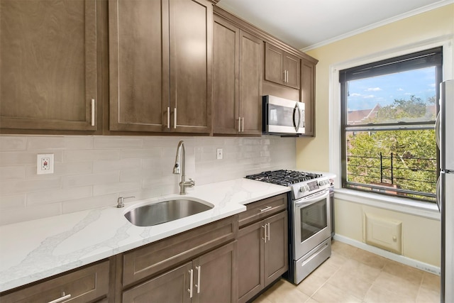 kitchen with stainless steel appliances, tasteful backsplash, a sink, and light stone countertops