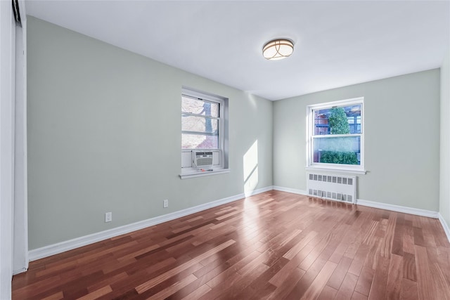 spare room with cooling unit, radiator, baseboards, and wood finished floors