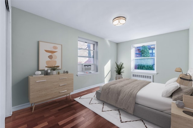 bedroom with dark wood-style floors, radiator heating unit, cooling unit, and baseboards