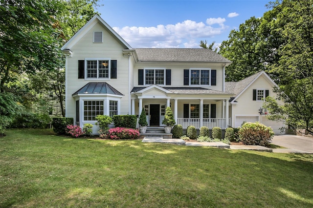 traditional-style house with an attached garage, covered porch, concrete driveway, and a front yard