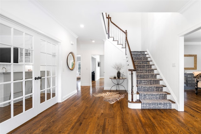 foyer entrance featuring dark wood-style floors, stairs, baseboards, and crown molding