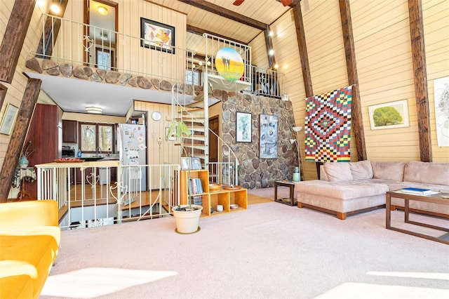 carpeted living room featuring high vaulted ceiling, wood ceiling, wood walls, and beam ceiling