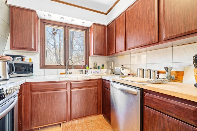 kitchen with ornamental molding, appliances with stainless steel finishes, a sink, and backsplash