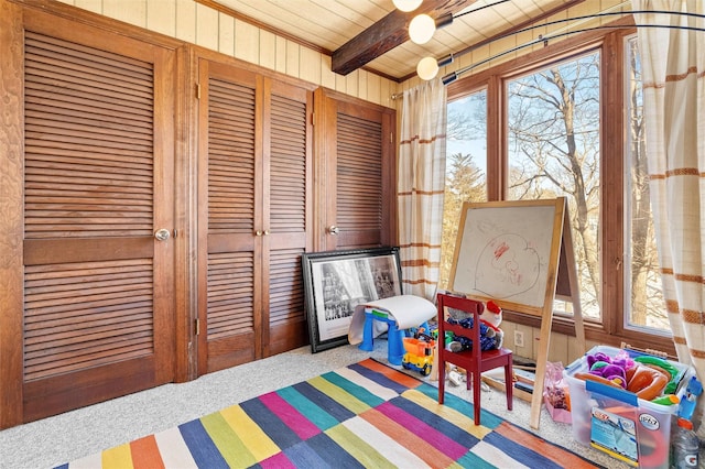 game room with carpet floors, wooden ceiling, beam ceiling, and wood walls