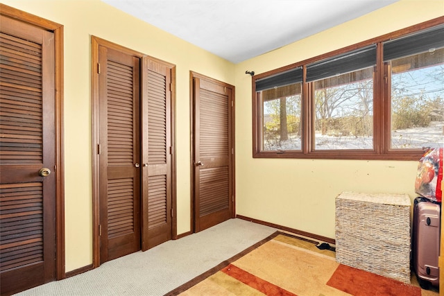 bedroom with baseboards, carpet floors, and multiple closets