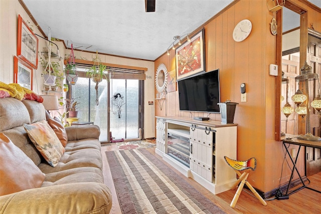 living room featuring light wood finished floors, wooden walls, and crown molding